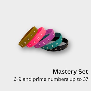 May include: A set of colorful silicone wristbands in olive green, pink, purple, teal, and black. Each band is printed with white numbers, including prime numbers up to 37. The text "Mastery Set" and "6-9 and prime numbers up to 37" are also visible.