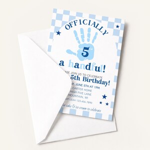May include: A white envelope partially reveals a blue and white birthday invitation. The invitation features the text "OFFICIALLY a handful!" with a handprint and the number 5. Additional text includes the date, time, and location of the birthday party.