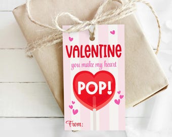 May include: A Valentine's Day gift tag with a pink and white striped background. The tag features the words "VALENTINE you make my heart POP!" in red and a red heart-shaped lollipop graphic. Small pink hearts are scattered around the tag.