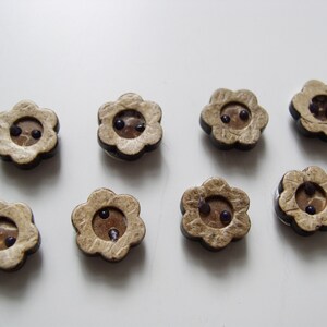 May include: Eight brown wooden flower-shaped buttons with two black centers.