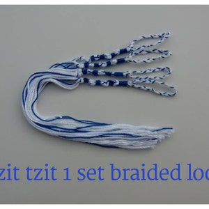 Puede incluir: Un conjunto de bucles trenzados blancos y azules, con el texto "Tzit tzit 1 set braided loop" en azul. Los bucles están hechos de hilos blancos y azules, con un diseño trenzado en la parte superior.