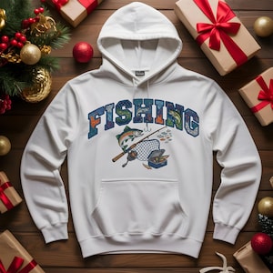 May include: White hooded sweatshirt with the word "FISHING" in a blue, green, and orange design. The graphic includes a fish, fishing rod, net, and tackle box. The sweatshirt has a front pocket and a drawstring hood.