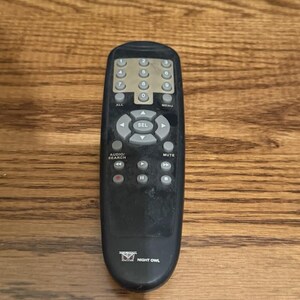 May include: A black Night Owl remote control featuring a numeric keypad, directional navigation buttons with a central SEL button, and playback controls. The device includes labels for Audio/Search, Mute, All, and Menu, with a small owl logo at the bottom.