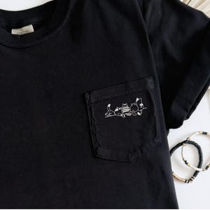 May include: A white ceramic mug with a black handle and the text "But First, Coffee" in a handwritten style. The mug is on a white surface. The mug is approximately 4 inches tall.