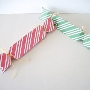 May include: Two paper Christmas crackers, one red and white striped and one green and white striped, tied with twine.