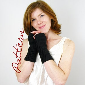 May include: A pair of black fingerless gloves made of crocheted yarn. The gloves are worn by a person with red hair.