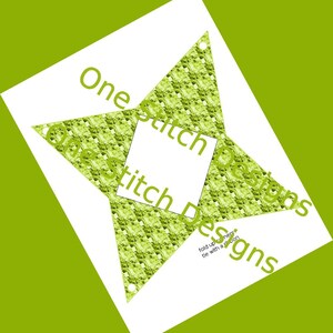 May include: A green and white star-shaped paper craft with the text "One Stitch Designs" printed on it. The text "fold up corners, tie with a ribbon" is also printed on the craft.