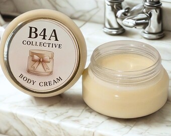 May include: A jar of body cream with the label "B4A Collective" and a cream-colored lid. The jar is open, revealing the cream inside. The background is a marble surface.
