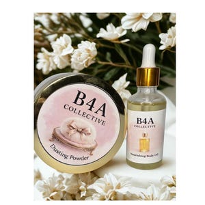 May include: A round gold-rimmed container of B4A Collective Dusting Powder with a pink label featuring a powder puff illustration, alongside a clear glass dropper bottle of B4A Collective Nourishing Body Oil with a gold cap and white label.