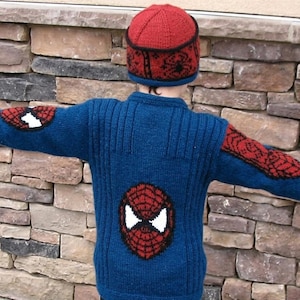 May include: A blue knitted sweater and matching hat with a Spider-Man design. The sweater features a large Spider-Man face on the back and web designs on the sleeves. The hat is red with a black web design.