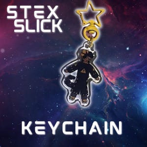 Puede incluir: Un llavero dorado con una estrella en la parte superior y una figura de una persona con ropa negra. El llavero está sujeto a un anillo dorado. Las palabras "STEX SLICK" y "KEYCHAIN" se muestran en blanco y en negrita.