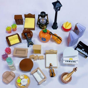 May include: A collection of miniature dollhouse furniture and accessories, including beds, sofas, tables, a piano, a guitar, a violin, and a lantern. The items are in various colors, such as brown, yellow, and white. The image also includes small potted plants and a drum.