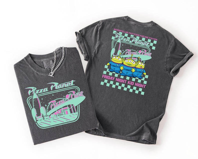 May include: Two dark gray t-shirts with Pizza Planet graphics. One shirt features a rocket and space diner design, the other has three green aliens and the text "Friday Night Kid Night". A silver chain necklace is on one shirt.