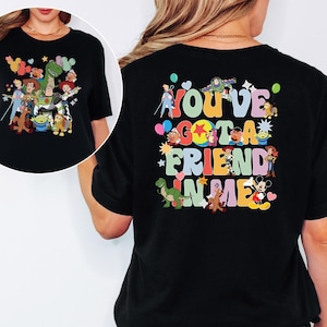 May include: Black t-shirt with a colourful graphic of Toy Story characters on the front and back. The back of the shirt features the text "You've Got A Friend In Me" in a playful font, with character illustrations.