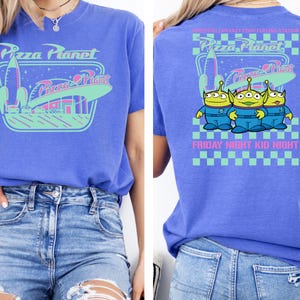 May include: A blue t-shirt featuring the Pizza Planet logo on the front and back. The front design includes a rocket ship and the words "Pizza Planet." The back of the shirt has three green aliens and the text "Friday Night Kid Night."