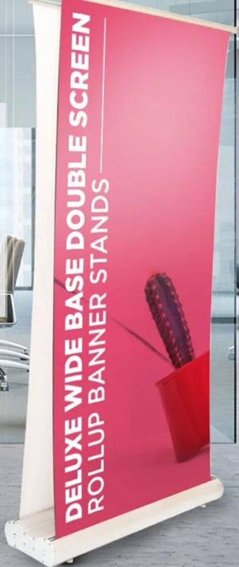 Może przedstawiać: Wysoki stojak na baner z białą ramą i żywym r&oacute;żowym wyświetlaczem. Na banerze znajduje się biały tekst: "DELUXE WIDE BASE DOUBLE SCREEN ROLLUP BANNER STANDS." Widoczny jest czerwony garnek z kaktusem.