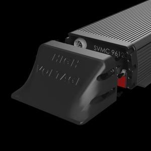Puede incluir: Primer plano de un dispositivo electrónico negro con el texto "HIGH VOLTAGE" en una cubierta desmontable. El dispositivo tiene una parte superior acanalada y el texto "SVMC 96120" impreso en el lateral. Se ve un interruptor rojo.