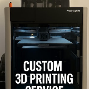 Puede incluir: Impresora 3D negra y plateada con el texto "CUSTOM 3D PRINTING SERVICE" y "SEND YOUR STL FILE". Tiene una parte superior transparente y una cama de impresión. La marca "Bamby" es visible.
