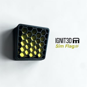 Könnte beinhalten: Ein schwarzes, quadratisches Objekt mit einem Wabenmuster auf der Vorderseite. Das Innere ist leuchtend gelb. Der Text "IGNIT3D Sim Flag" wird in Schwarz und Grün auf weißem Hintergrund angezeigt.