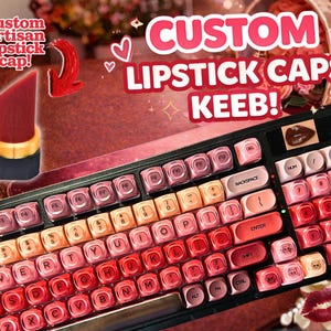May include: A custom keyboard with lipstick-themed keycaps in a gradient of red, pink, and orange. The keyboard has a black frame and features a lipstick-shaped artisan cap. Text on the image reads "CUSTOM LIPSTICK CAPS KEEB!"