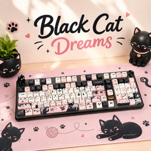 May include: A black and pink keyboard with cat-themed keycaps, a matching mousepad, and decorative cat figurines. The keyboard has the text "Black Cat Dreams" on the wall behind it. The keycaps feature cat illustrations.