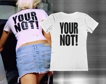 Peut inclure: Un t-shirt blanc à manches courtes avec l'inscription "YOUR NOT!" imprimée en lettres capitales noires et grasses au dos. Le vêtement présente un col rond et une coupe standard, mettant en valeur le graphisme sur le tissu blanc uni.