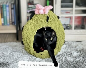 Könnte beinhalten: Eine schwarze Katze liegt in einer grünen, gehäkelten Katzenhöhle mit einem rosa Blumenakzent. Die Katzenhöhle ist rund mit einer großen Öffnung. Der Text "PDF DIGITAL DOWNLOAD" befindet sich unten im Bild.