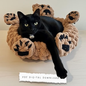May include: A black cat rests in a tan, plush pet bed shaped like a bear. The bed features large paw-shaped accents in a darker brown. The text "PDF DIGITAL DOWNLOAD" is at the bottom.