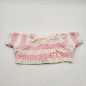 May include: A pink and white striped knit top with short sleeves. The top features a small embroidered logo that says "Cabbage Patch Kids". The neckline is trimmed with a delicate lace detail. The garment is designed for a doll.