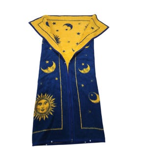 May include: A deep blue sleeping bag featuring a yellow celestial pattern of suns, moons, and stars. The interior lining is yellow with a matching blue celestial print. The bag has a central vertical zipper and small metal snaps along the edges.