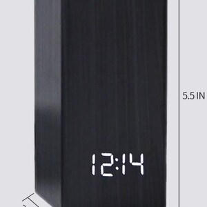 May include: A black rectangular desk organiser with a digital clock displaying 12:14. The organiser is 14 cm tall and 7 cm wide and deep.