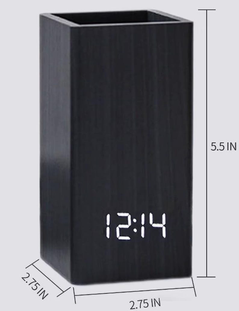 May include: A black rectangular desk organiser with a digital clock displaying 12:14. The organiser is 14 cm tall and 7 cm wide and deep.