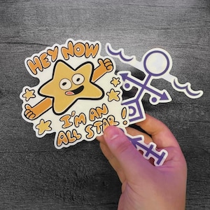 May include: Two stickers are shown. One is a cartoon star with the text "Hey Now I'm an All Star!" The star is yellow with orange arms and a smiling face. The second sticker is purple and white with a symbol.