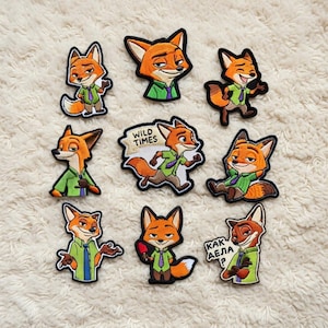 Könnte beinhalten: Eine Sammlung von neun gestickten Aufnähern mit einem orangefarbenen Fuchs-Charakter in verschiedenen Posen. Der Fuchs trägt ein grünes Hemd und eine lila Krawatte. Ein Aufnäher hat den Text "WILD TIMES". Die Aufnäher befinden sich auf einer weißen, strukturierten Oberfläche.