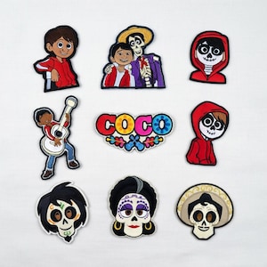 May include: Nine embroidered patches featuring characters from the animated film "Coco." The patches include images of Miguel, Hector, and other characters, along with the film's logo. The patches are in various shapes and sizes, with vibrant colours.