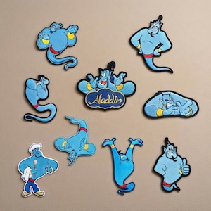 May include: A collection of embroidered patches featuring the Genie from Disney's Aladdin. The patches are primarily blue with accents of red, yellow, and black. Various poses and designs are shown, including the Aladdin logo.