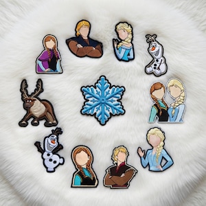May include: A collection of embroidered patches featuring characters and symbols from the animated film. The patches include images of Anna, Elsa, Kristoff, Olaf, Sven, and a blue snowflake. Each patch has a black border and is set against a white, fluffy background.