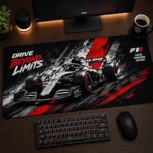 May include: A rectangular desk mat featuring a black, white, and red graphic of a Formula 1 race car. The text "DRIVE BEYOND LIMITS" is printed on the left, while "P1 FOCUS PRECISION VICTORY" appears on the right side of the mat surface.