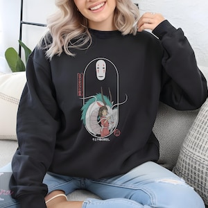 May include: Black sweatshirt featuring a graphic from the animated film, Spirited Away. The design includes the character No-Face, a dragon, and a girl in a red outfit. Japanese text is also included in the design.