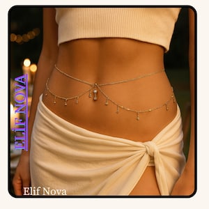 May include: A delicate gold-toned body chain with dangling charms and a central pendant. The chain is worn around the waist, accentuating the midriff. The image includes the text "Elif Nova".