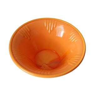 May include: An orange bowl with a smooth, glossy finish. The interior features a series of hand-shaped indentations. The bowl's design is simple and functional, suitable for serving or display.