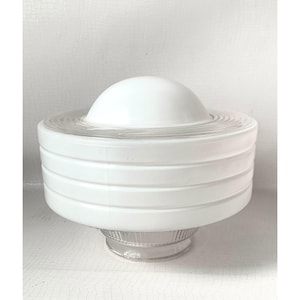 May include: A white glass light fixture shade featuring a central dome top, a wide cylindrical body with three horizontal raised bands, and a clear, ribbed glass base designed for mounting. The shade has a smooth, opaque finish throughout.