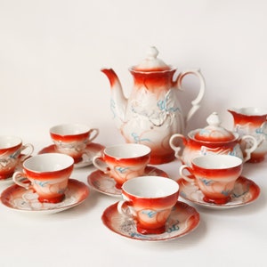 Peut inclure: Un service à thé vintage avec un fond blanc et des motifs floraux rouges et bleus. L'ensemble comprend une théière, un pot à crème, un sucrier et six tasses à thé et soucoupes.