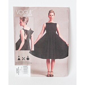 May include: Vogue Patterns sewing pattern featuring a black dress design. The pattern includes a full-length image of the dress and a smaller inset image. The pattern is designed by Andrea Katz Objects. The pattern number is V1102.