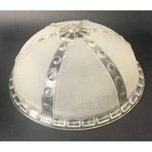 May include: A dome-shaped glass light fixture shade with a frosted finish. The shade features clear, raised vertical ribs decorated with a series of circular indentations, meeting at a central circular finial with a radiating sunburst pattern.