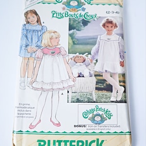 May include: Vintage Cabbage Patch Kids sewing pattern for a white dress with pink trim and a blue gingham dress. The pattern is for sizes 2-3-4 and includes iron-on transfers. The pattern is from Butterick.