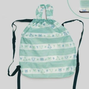 May include: A drawstring backpack and a matching folded item, both in a light green and white striped pattern. The pattern includes small animal and shape illustrations. The backpack has dark green straps and a drawstring closure.