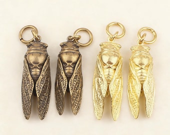 Puede incluir: Cuatro colgantes metálicos de cigarra. Dos son de color bronce y dos de color dorado. Cada colgante tiene un diseño detallado de insecto con alas y un lazo para colgar. Los colgantes se muestran sobre un fondo liso.