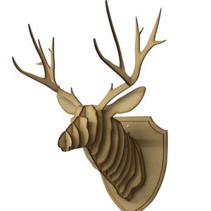 May include: A wooden deer head wall mount with a layered design. The deer head is light brown and mounted on a shield-shaped plaque. The antlers are long and pointed, and the ears are upright.