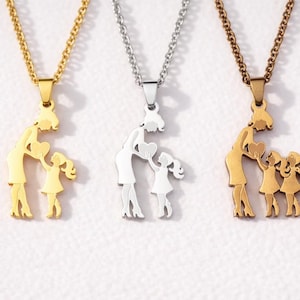 Puede incluir: Tres collares con diseños de colgantes. Los colgantes representan una figura materna y un niño, o varios niños. Los collares son de color oro, plata y bronce. Las cadenas son delicadas y los colgantes son siluetas recortadas.